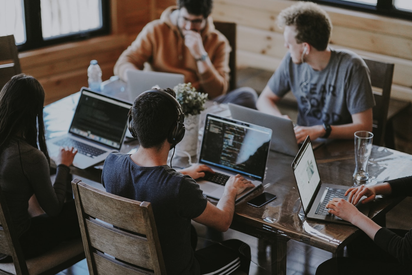 Colleagues collaborating around laptops in a modern workspace.